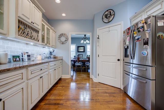 kitchen with stainless steel fridge, a notable chandelier, backsplash, and dark hardwood / wood-style floors