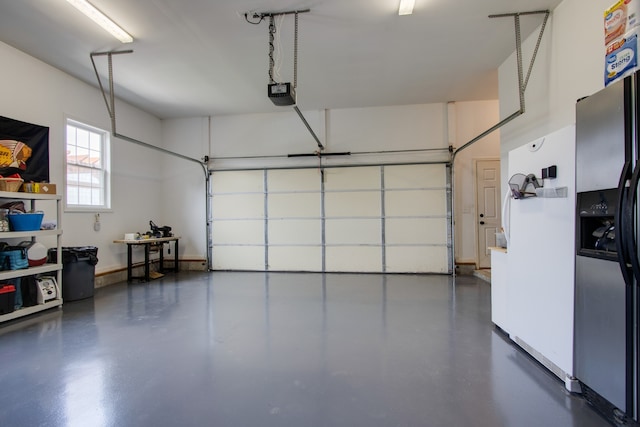 garage with a garage door opener and stainless steel refrigerator with ice dispenser