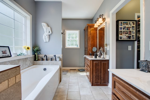 bathroom with vanity, tile floors, and tiled tub