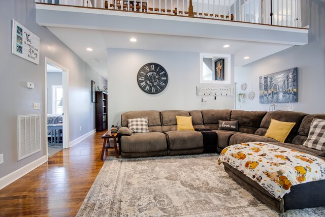 living room with dark hardwood / wood-style flooring and a towering ceiling