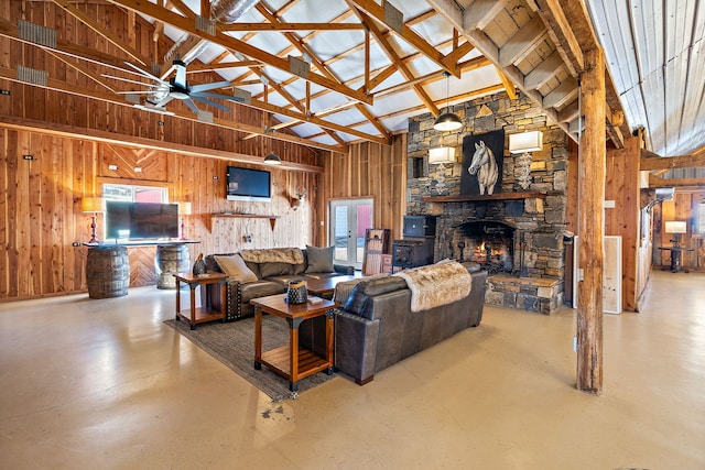 living room with wood walls, high vaulted ceiling, ceiling fan, and a fireplace