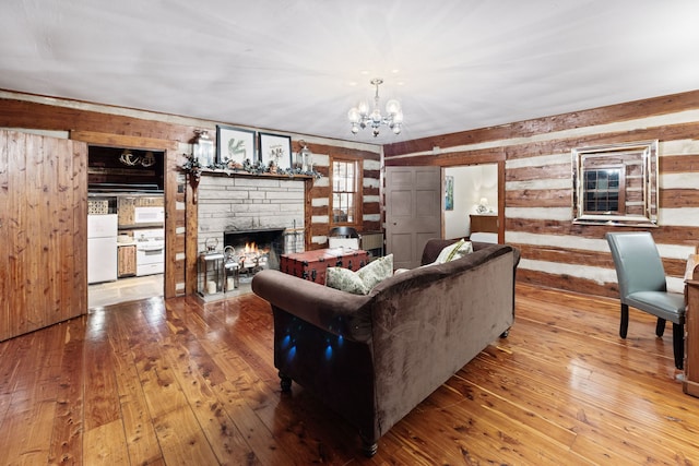 living room featuring hardwood / wood-style floors, a stone fireplace, and a chandelier