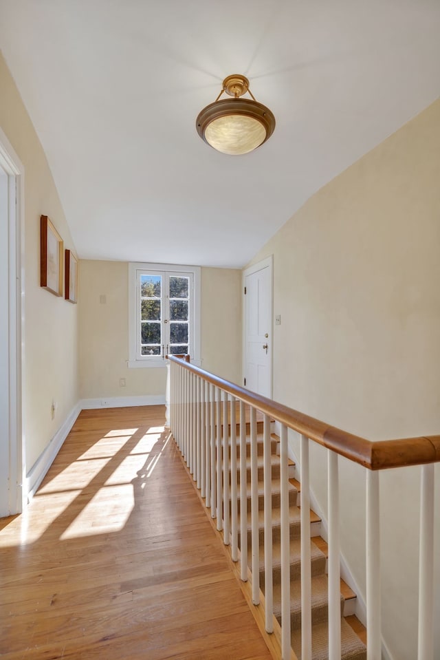 hallway with lofted ceiling and light hardwood / wood-style floors