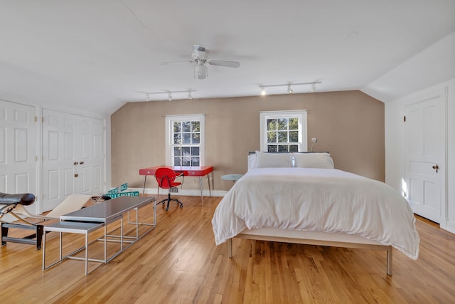 bedroom featuring light hardwood / wood-style flooring, ceiling fan, track lighting, and lofted ceiling