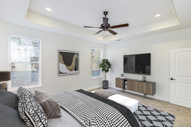 carpeted bedroom featuring a raised ceiling and ceiling fan