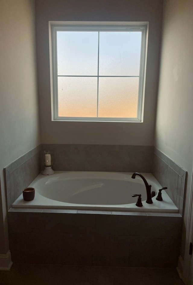 bathroom featuring tiled bath and a healthy amount of sunlight