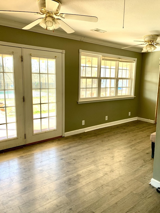 spare room featuring a healthy amount of sunlight, ceiling fan, and hardwood / wood-style floors