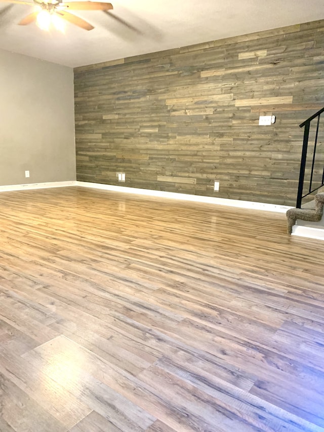 spare room featuring hardwood / wood-style flooring, wooden walls, and ceiling fan