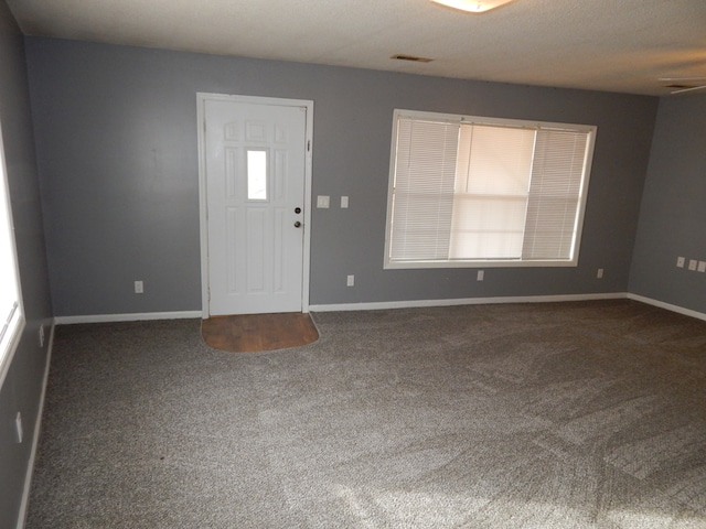 foyer with dark colored carpet and a textured ceiling