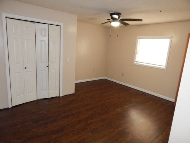 unfurnished bedroom featuring dark hardwood / wood-style floors, ceiling fan, and a closet