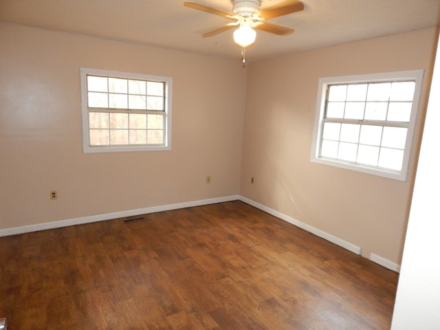 spare room featuring ceiling fan, dark hardwood / wood-style flooring, and a wealth of natural light