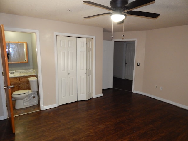 unfurnished bedroom featuring connected bathroom, ceiling fan, a closet, and dark wood-type flooring