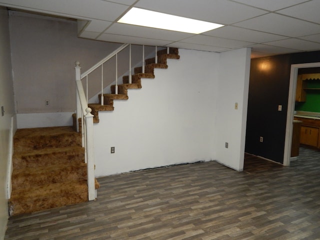 basement with a paneled ceiling and dark hardwood / wood-style floors