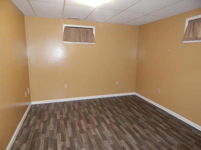 basement featuring a paneled ceiling and dark hardwood / wood-style flooring