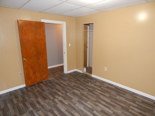 spare room with a drop ceiling and dark wood-type flooring