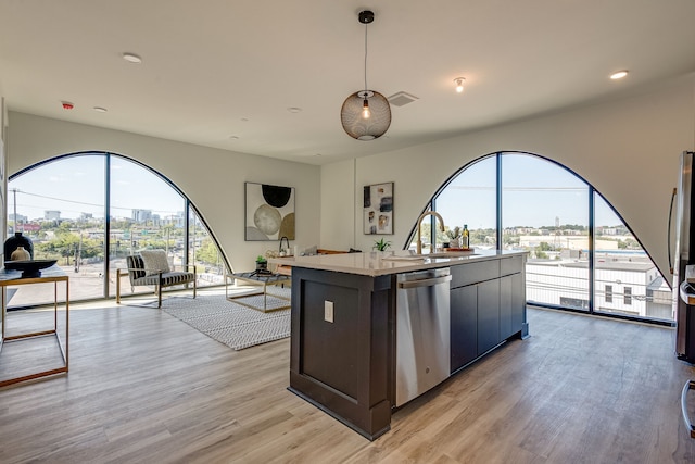 kitchen featuring light hardwood / wood-style floors, stainless steel dishwasher, sink, and a kitchen island with sink