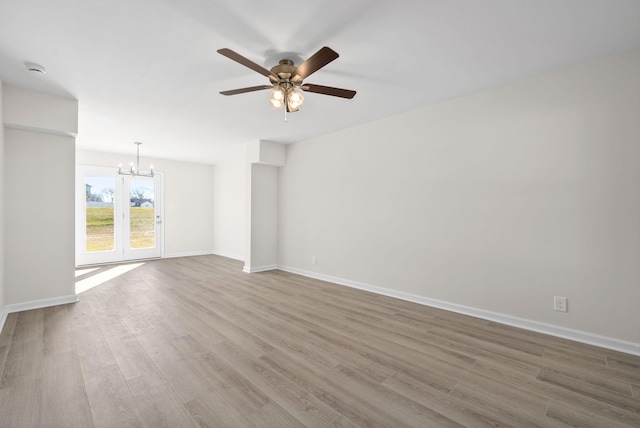 spare room with ceiling fan with notable chandelier and hardwood / wood-style flooring