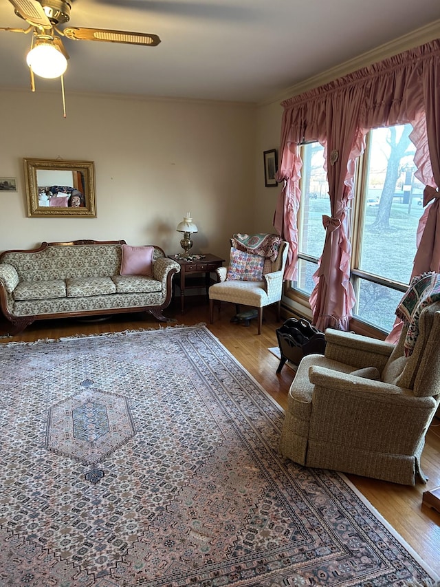 living room featuring wood-type flooring, ornamental molding, and ceiling fan