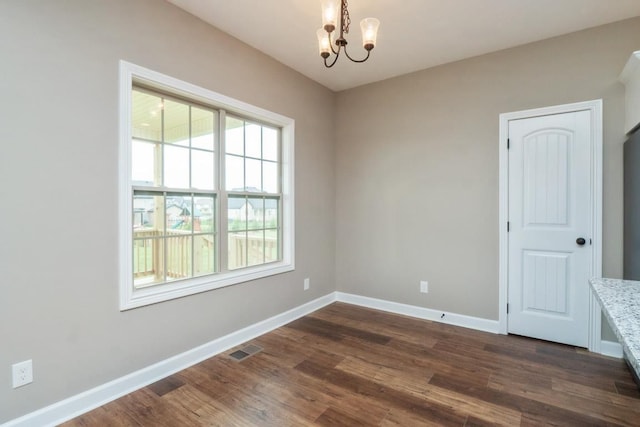 empty room featuring dark hardwood / wood-style flooring and a notable chandelier