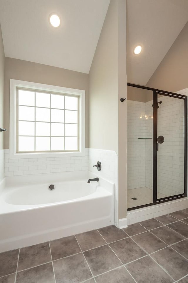 bathroom with tile patterned flooring, shower with separate bathtub, a wealth of natural light, and vaulted ceiling