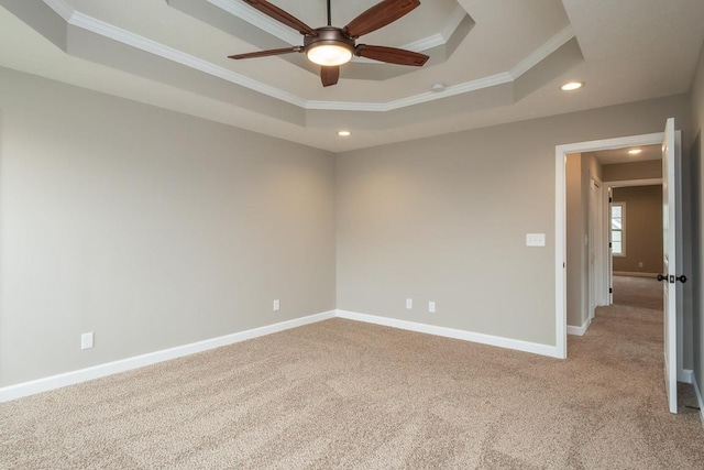 carpeted spare room with ceiling fan, crown molding, and a tray ceiling