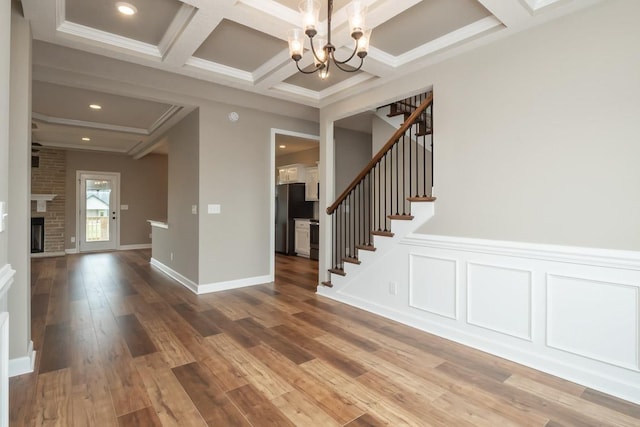 interior space featuring coffered ceiling, crown molding, beam ceiling, hardwood / wood-style flooring, and an inviting chandelier