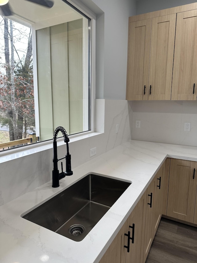 kitchen with sink, tasteful backsplash, light brown cabinets, dark hardwood / wood-style flooring, and light stone countertops