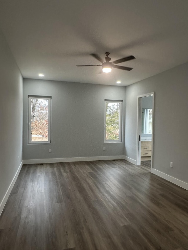 empty room with plenty of natural light, dark hardwood / wood-style floors, and ceiling fan