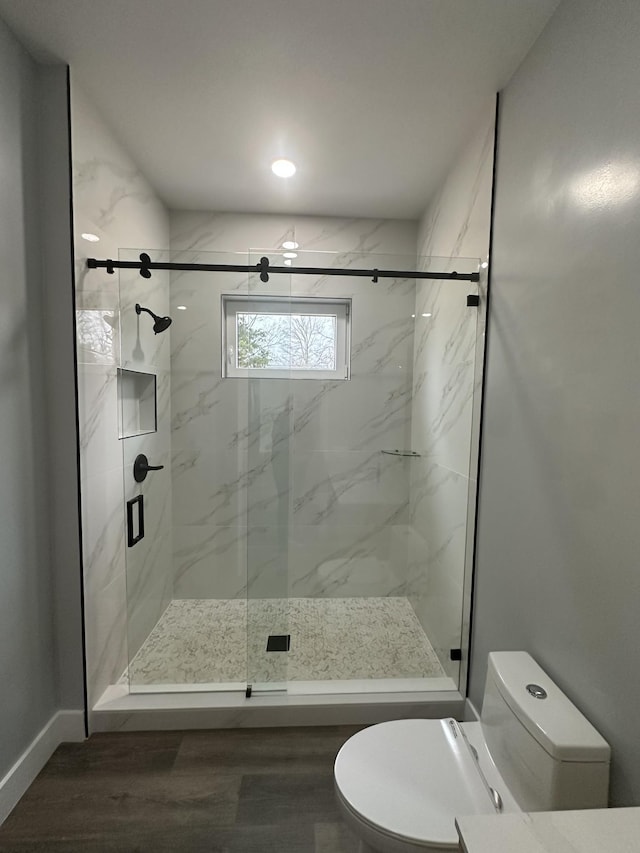 bathroom with walk in shower, toilet, and hardwood / wood-style floors