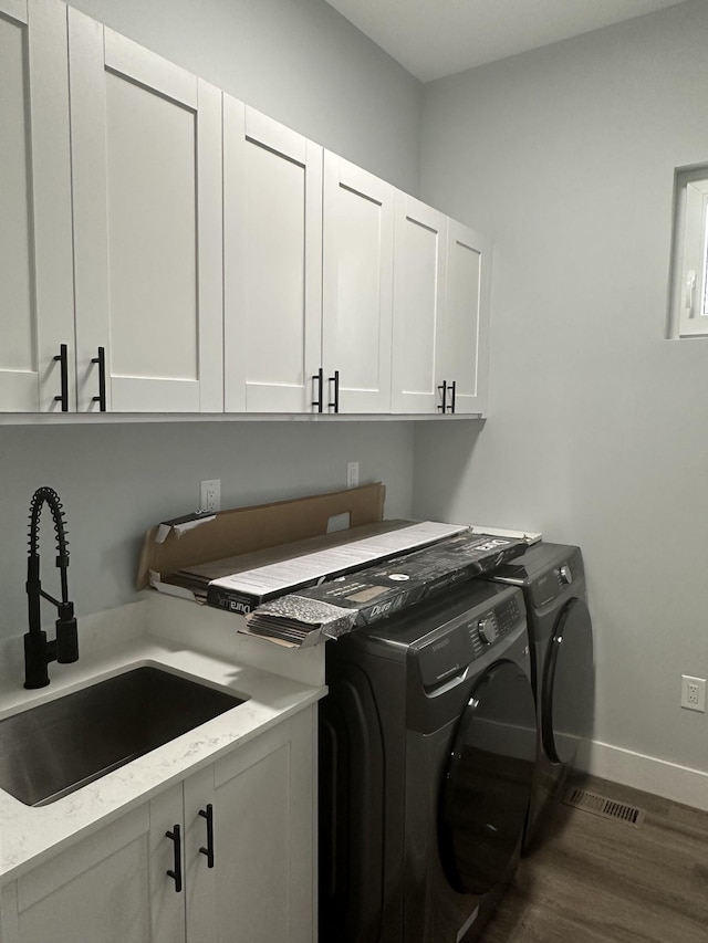 washroom featuring sink, dark hardwood / wood-style floors, cabinets, and washing machine and clothes dryer