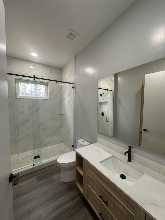 bathroom with hardwood / wood-style flooring, vanity, walk in shower, and toilet