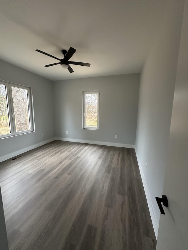 empty room with ceiling fan and dark hardwood / wood-style flooring