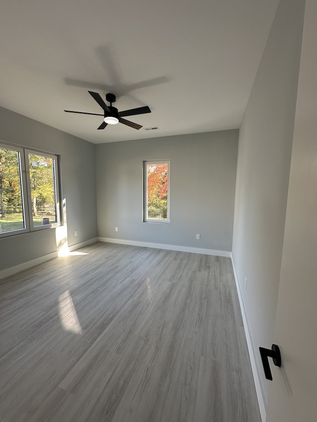 empty room with ceiling fan, a healthy amount of sunlight, and light wood-type flooring