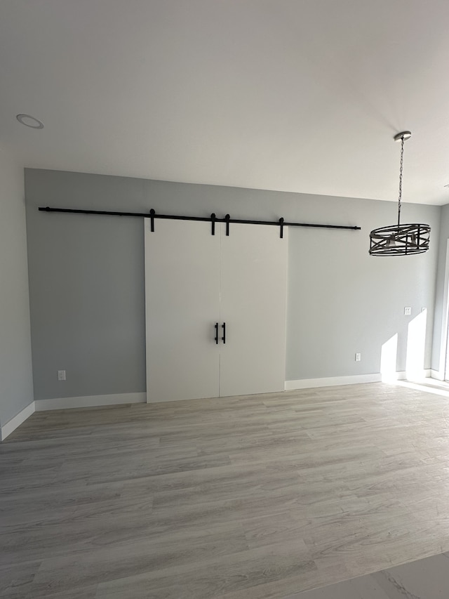 empty room with a barn door and light hardwood / wood-style flooring