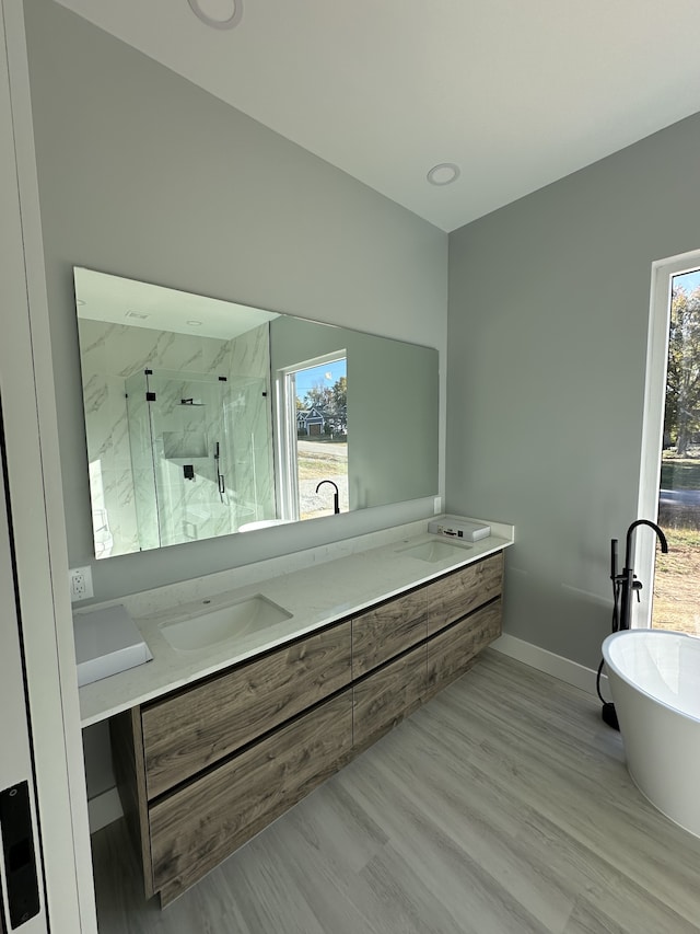 bathroom with hardwood / wood-style flooring, vanity, and plus walk in shower