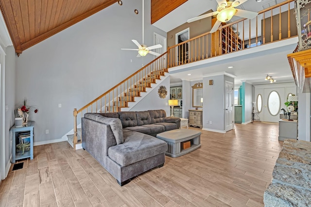 living room with crown molding, light hardwood / wood-style flooring, ceiling fan, and a towering ceiling