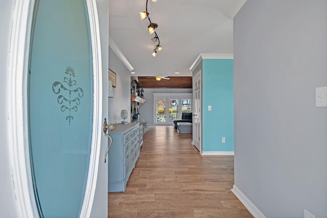 hallway featuring ornamental molding, track lighting, and light hardwood / wood-style floors