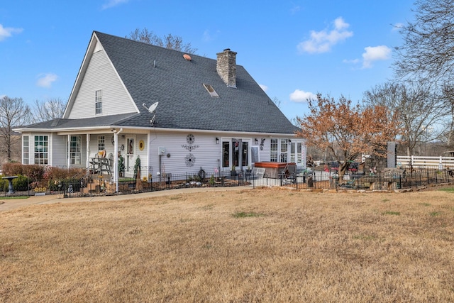 rear view of property featuring a hot tub and a yard