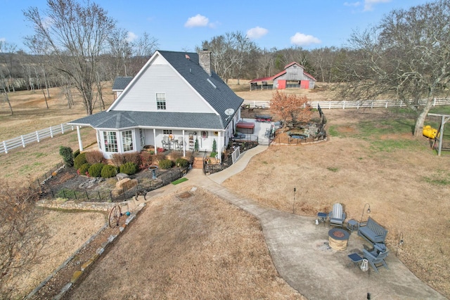 view of front facade with a rural view, covered porch, and a fire pit