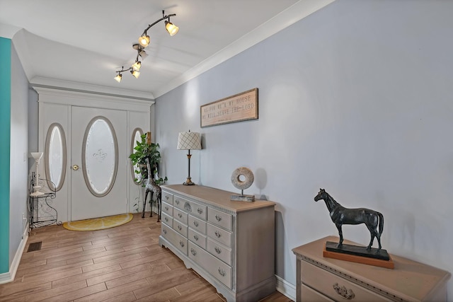 foyer featuring crown molding, rail lighting, and light hardwood / wood-style flooring