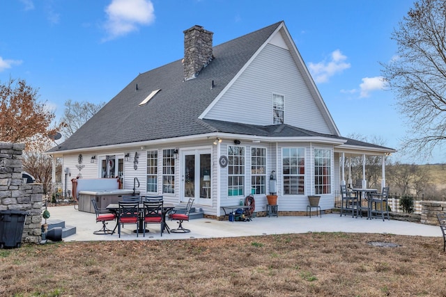 rear view of house featuring a hot tub, a patio area, and a lawn