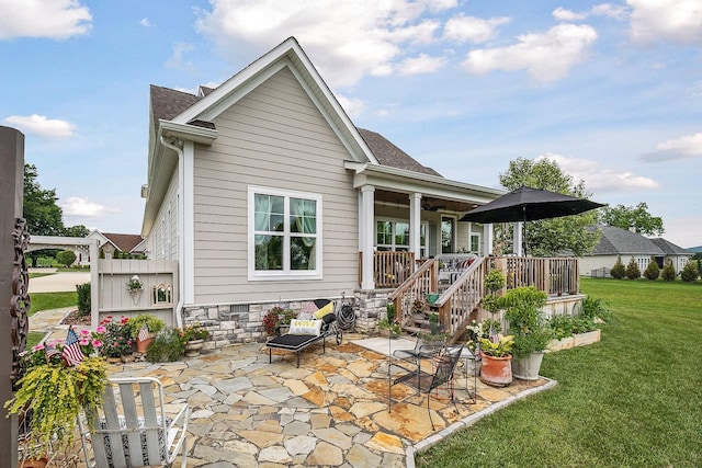 rear view of property featuring a yard, covered porch, and a patio area