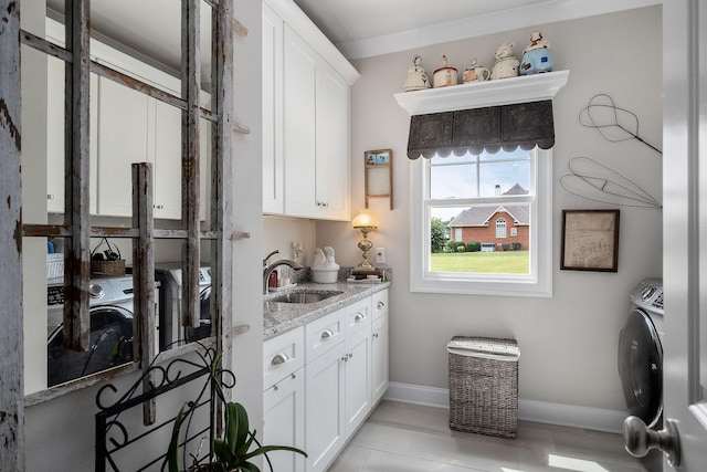 interior space with washer / dryer, sink, white cabinets, and light stone counters