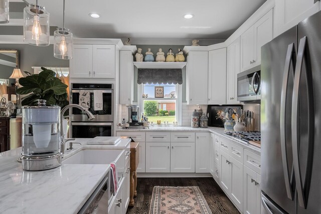 kitchen with white cabinetry, appliances with stainless steel finishes, light stone countertops, and dark wood-type flooring