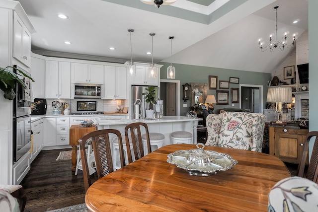 dining space with dark wood-type flooring, lofted ceiling, sink, and a notable chandelier