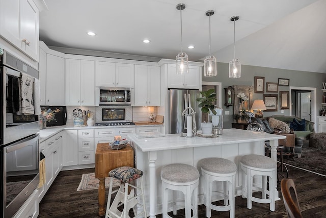 kitchen featuring hanging light fixtures, a kitchen island, appliances with stainless steel finishes, and white cabinets