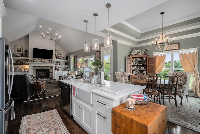 kitchen with white cabinetry, appliances with stainless steel finishes, a chandelier, and a center island with sink