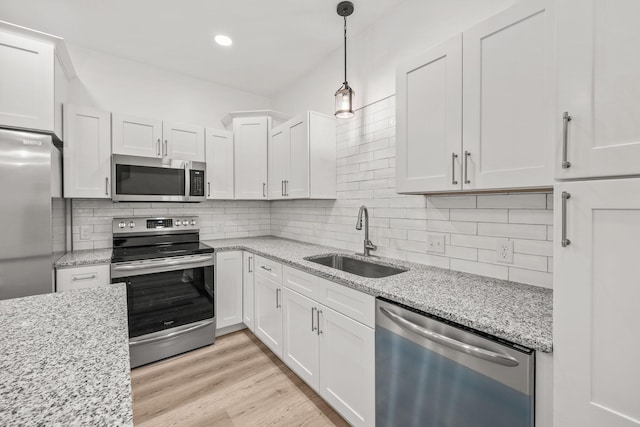 kitchen featuring white cabinetry, sink, light hardwood / wood-style flooring, pendant lighting, and appliances with stainless steel finishes