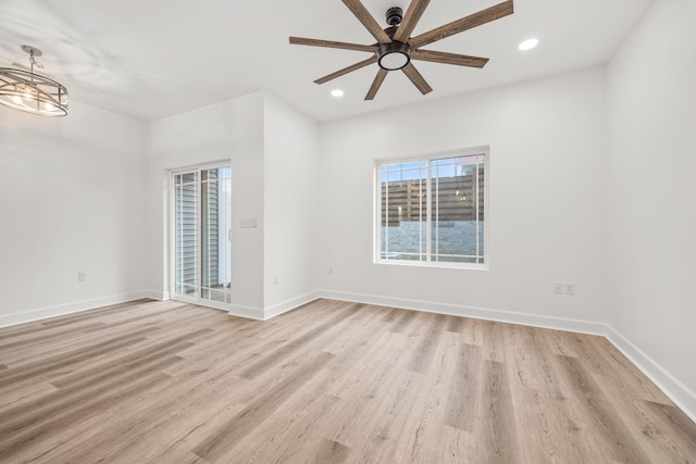 unfurnished room featuring ceiling fan with notable chandelier and light wood-type flooring