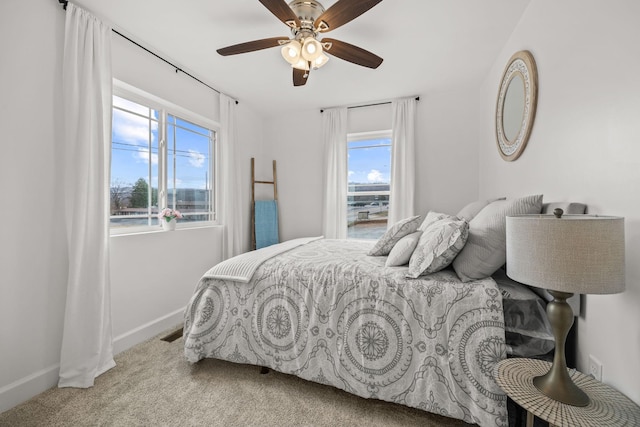 bedroom with ceiling fan, light colored carpet, and multiple windows